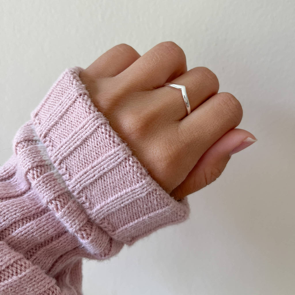 Minimalist sterling silver chevron ring elegantly worn on a hand with a cozy pink sweater